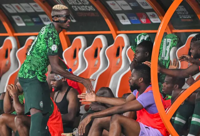 Osimhen high five players on the Nigeria bench after being subbed.