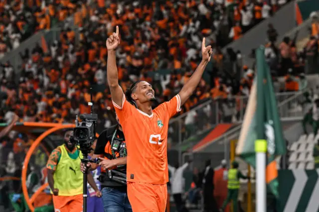 Sebastie  Haller points to the sky as he celebrates an Ivory Coast goal with the fans in the corner of the pitch.