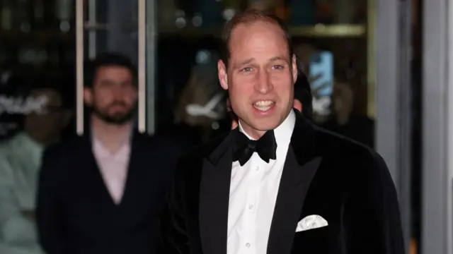 Dressed in black tie, Prince William smiles after arriving for a fundraising event