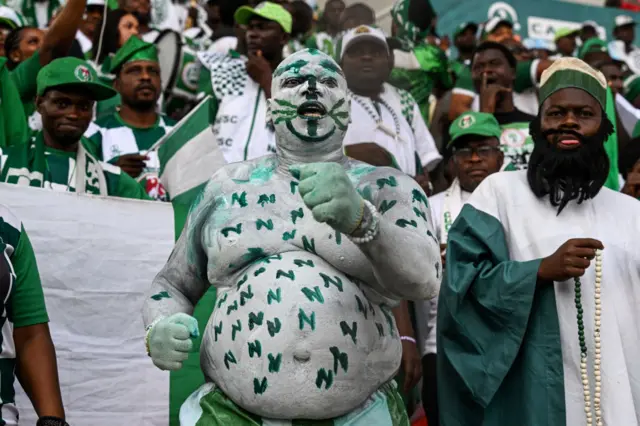 A Nigeria fan painted head to toe in the team's colours with green 'N' dotted around his torso.