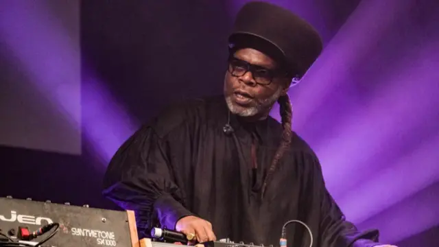 Jazzie B spins a DJ deck on stage