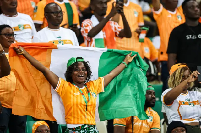 An ivory coast fan holds a team flag in the stands.