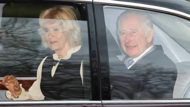 King Charles and Queen Camilla sitting in the back seat of a car