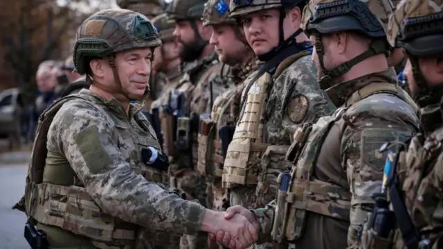 Oleksandr Syrskyi (L), the commander of the Ukrainian Ground Forces, shakes hands with Ukrainian servicemen during a flag raising ceremony in the recently recaptured city of Lyman, Donetsk region, eastern Ukraine, 04 October 2022 (reissued 08 February 2024).