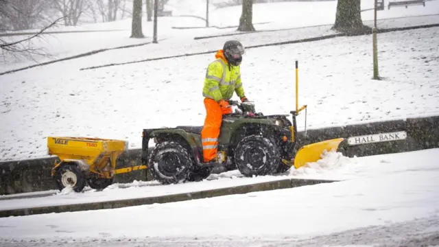 Person riding a snow-plough equipped quad bike in Buxton, Peak District