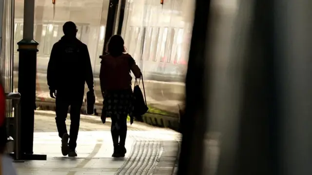 Passengers wait to board a train at Manchester Piccadilly Station