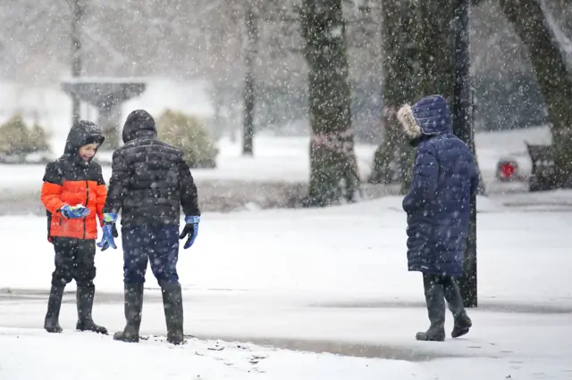 Children enjoying the snow in Pavilion Gardens, Buxton, Peak District.