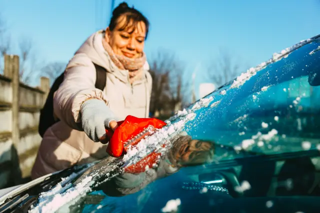 A woman de-icing her car