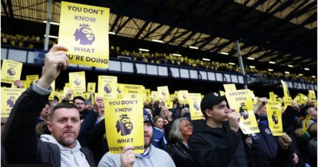 Everton fans hold up signs in protest against the Premier League