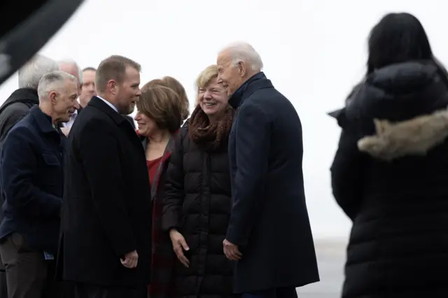 Biden, Smith and others standing outside in dark jackets