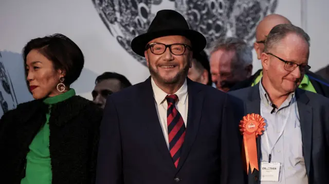 Candidate George Galloway, leader of the Workers Party of Britain, smiles at a polling station