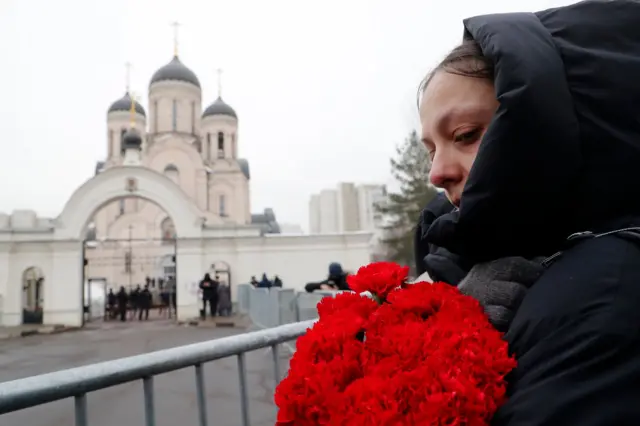 A woman with red flowers near the church in Moscow where Alexei Navalny's funeral service is expected to be held