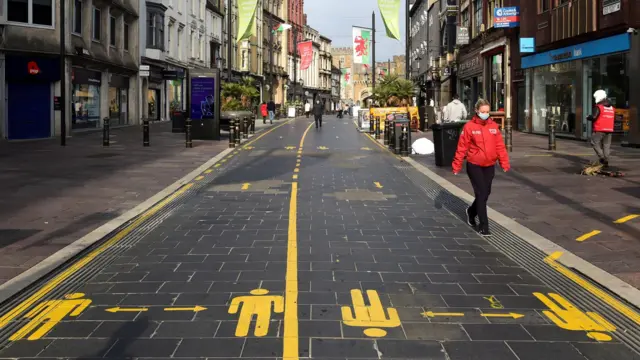 A person wears a face mask as they walk through Cardiff city centre