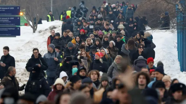 Dozens of people walk through the snow to get to the Borisovskoye cemetery, where Alexi Navlany was buried today