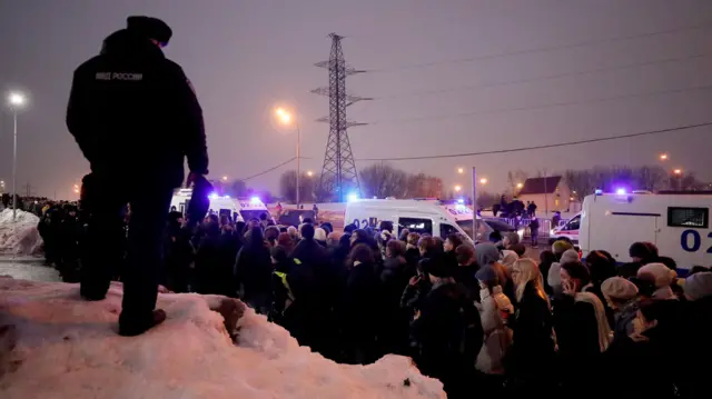 Crowds of people gather near police vans after Navalny's funeral