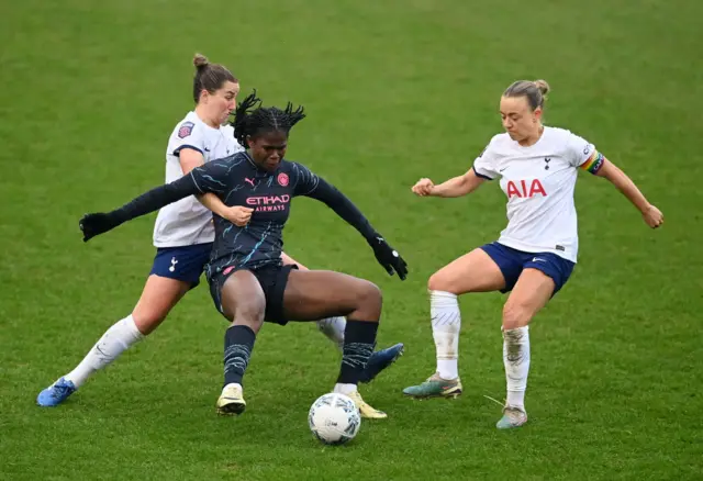 Two Spurs defenders pressure Bunny Shaw who is trying to shield the ball.