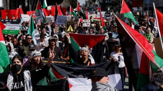 A large crowd of people holding Palestinian flags and holding anti-war placards