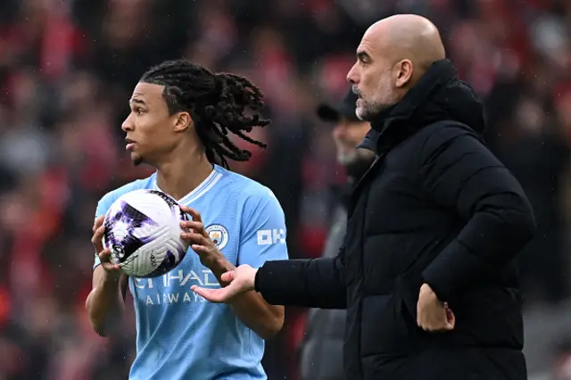 Pep Guardiola (R) passes a stray ball to Manchester City's Dutch defender #06 Nathan Ake