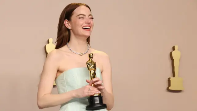 Emma Stone holds her Oscar, smiling