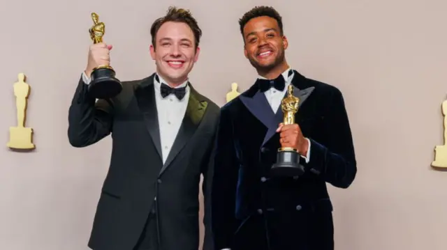 Ben Proudfoot and Kris Bowers smile with their Oscars