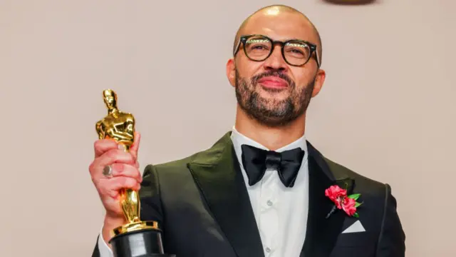 Cord Jefferson grins as he holds his Oscar