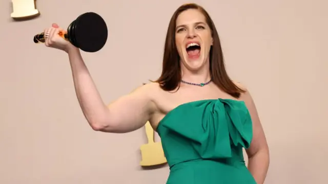 Jennifer Lame holds her award in the air, smiling