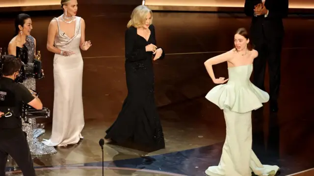 Emma Stone gestures toward her dress as she wins the Oscar for Best Actress for "Poor Things" during the Oscars show at the 96th Academy Awards in Hollywood, Los Angeles, California, U.S., March 10, 2024