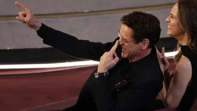 Robert Downey Jr points towards the stage as he laughs