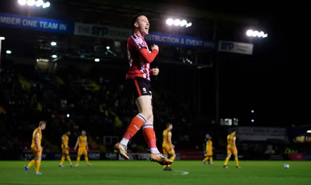 Jack Moylan celebrates scoring for Lincoln against Cambridge