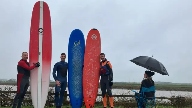 Surfers posing with their boards next to the River Severn