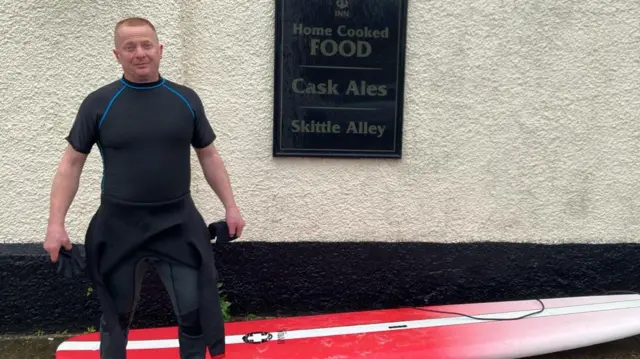 Steve Ball with a surfboard ahead of the bore