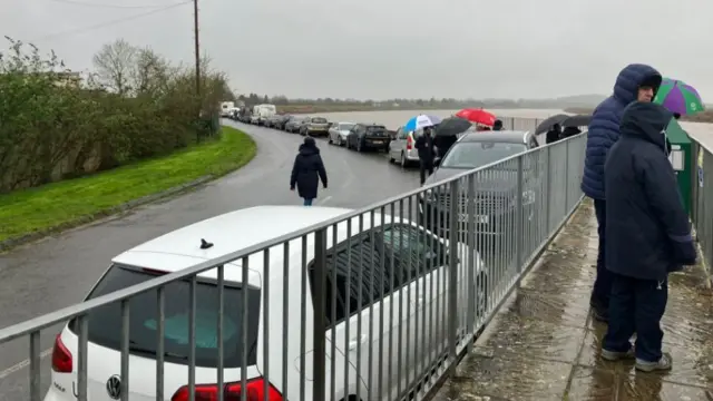 People and cars along the River Severn preparing to watch the Severn bore