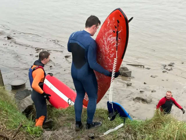 Surfers entering the river