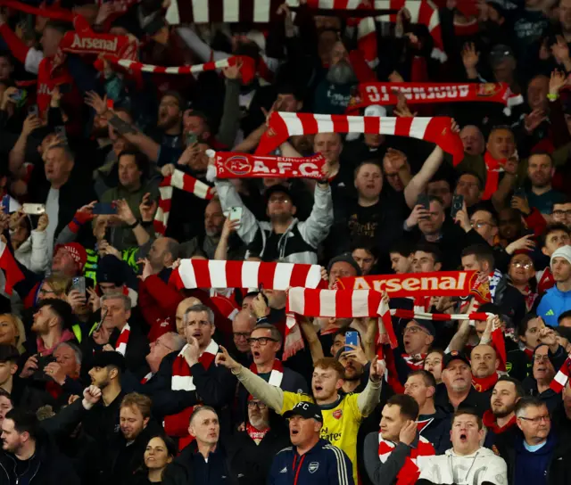 Arsenal fans hold scarves aloft.