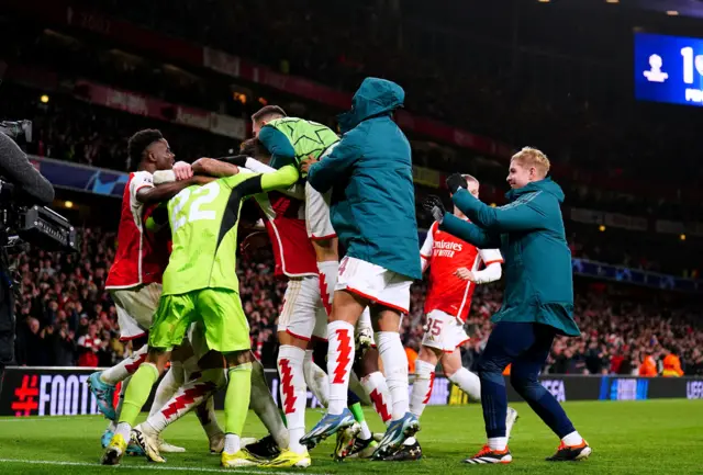 Arsenal players mob Raya after his heroics.