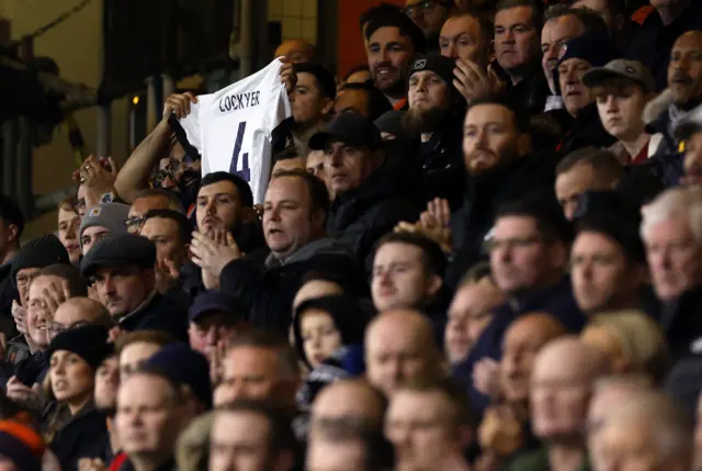 A fan holds a Tom Lockyer shirt up in the stands during the moments applause.