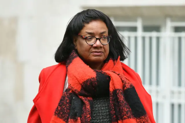 Diane Abbott pictured wearing a red coat and scarf in April 2023