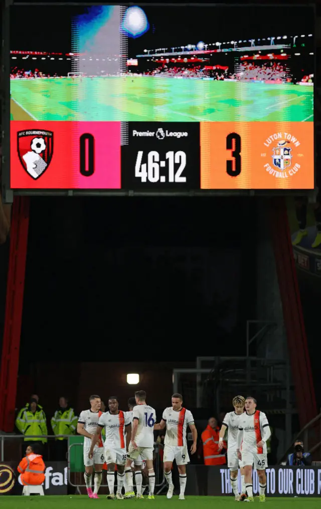 Luton celebrate under the scoreboard that reads 3-0 to Luton.