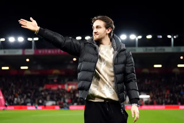 Tom Lockyer walks around the pitch waving to the fans.