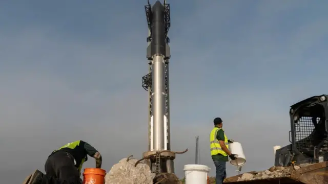 Workers remove rocks and debris from the surrounding area as SpaceX's next-generation Starship spacecraft atop its powerful Super Heavy rocket is prepared for a third launch