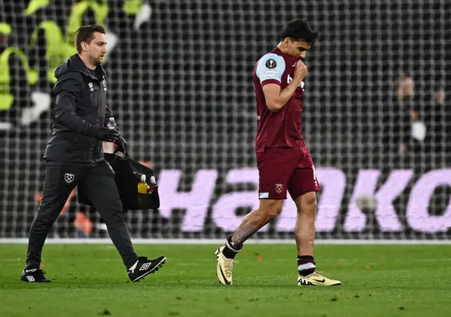 Paqueta covers his mouth with is shirt as he limps off after receiving treatment