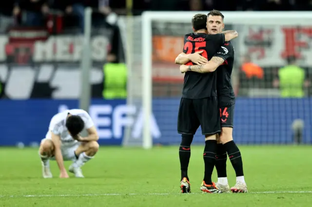 Leverkusen playwrs celebrate as a Qarabag player sinks to his knees.