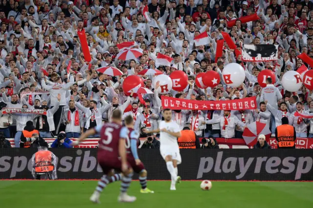 Freiburg fans sing in numbers behind the goal.