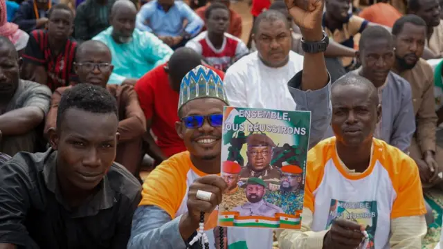 A worshipper displays a poster that reads 'Together we will succeed' during a Koranic lecture for the junta during Friday prayer at a mosque in Niamey, Niger, 11 August 2023.