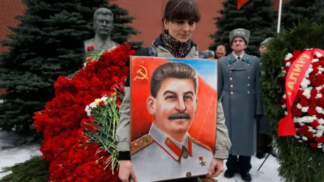 A woman holds a portrait of Stalin at the Stalin memorial in Moscow.