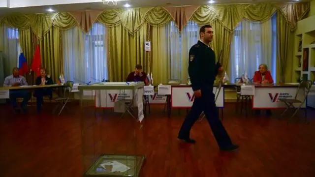 A police officer walks past a ballot box at a polling station during Russia's presidential election in Saint Petersburg on 17 March 2024