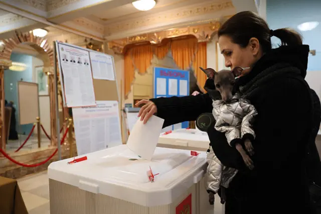 A woman casts her ballot with her dog in Russia's presidential election at a polling station in Moscow on 17 March 2024