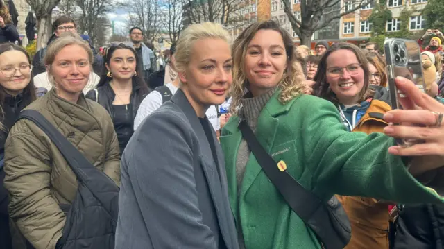 Yulia Navalnaya is posing with the people in the line at noon to vote in Russian elections