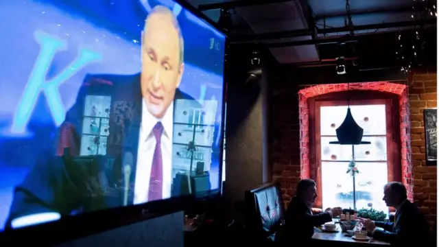 Putin on a large TV screen.