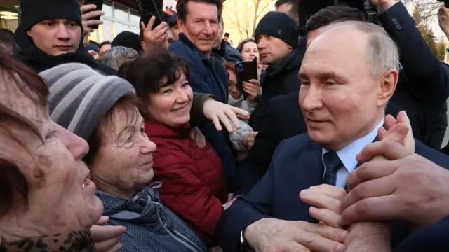 Putin meets with local residents, and holds one elderly woman’s hand